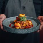 A chef holding a plate of food with natural male enhancement products