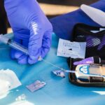 person using disposable syringe put specimen on blue and white glucose meter