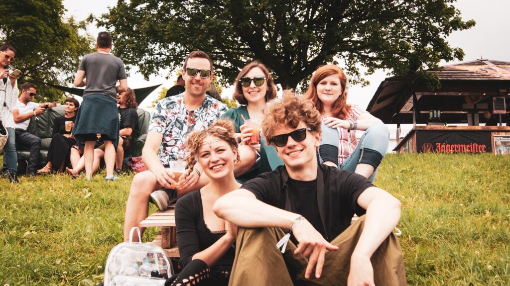 happy people sitting on grass field at day