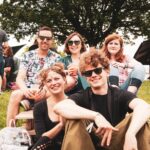 happy people sitting on grass field at day