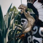 Native Mexican Aztec warrior, with pre-Hispanic makeup simulating a skull and a bone headdress adorned with feathers and cempazuchil flowers