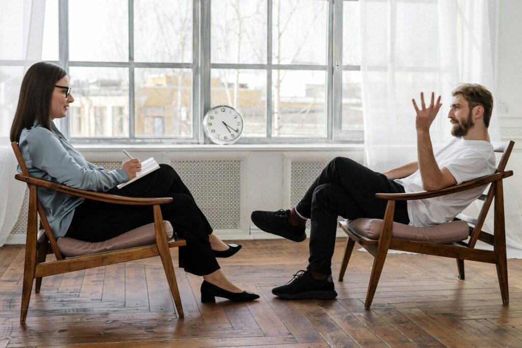 A psychologist engaging in a counseling session with a male patient to support mental health.